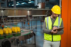 serious male worker writing on clipboard at juice factory